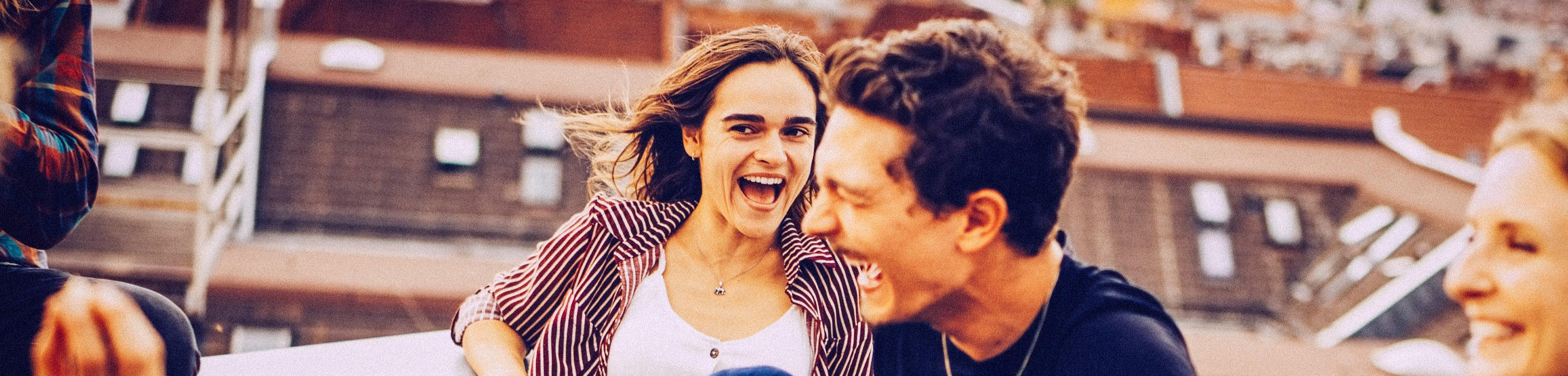 A group of happy friends sit and laugh together on a rooftop desktop
