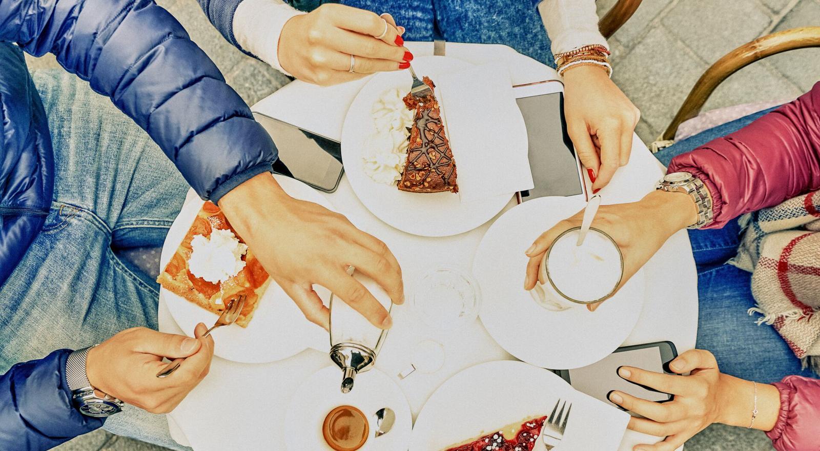 Large Web and Screen Overhead view of a group of people eating cake and drinking coffee at an outside table