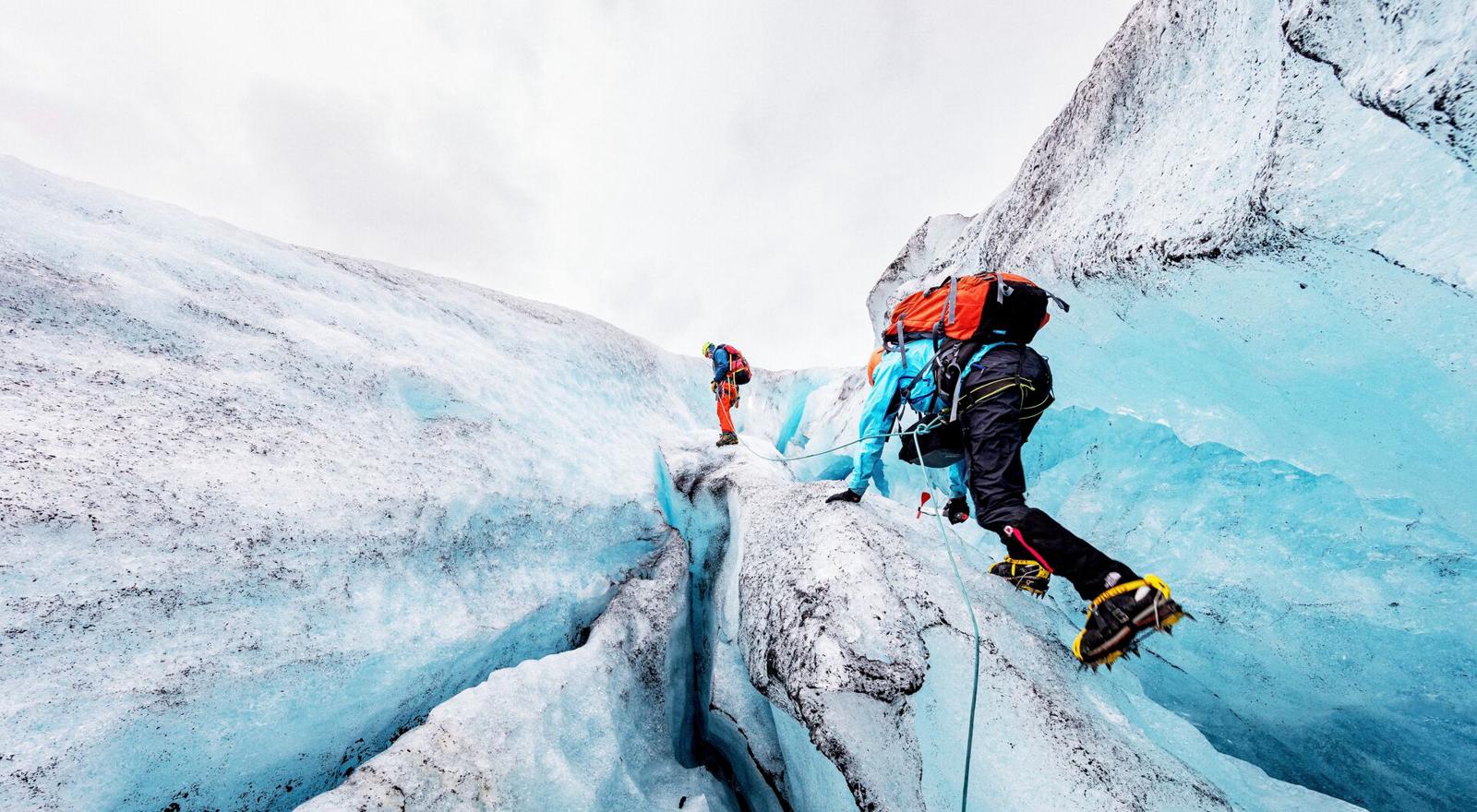 Large Web and Screen Two people with safety equipment are climbing a glacier