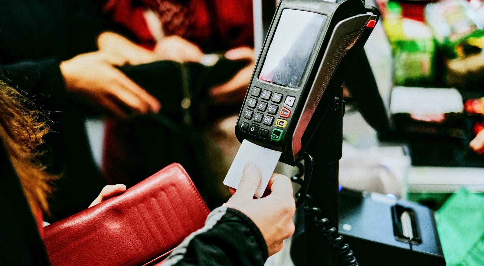 Large Web and Screen Woman putting a debit card in a payment terminal in the supermarket