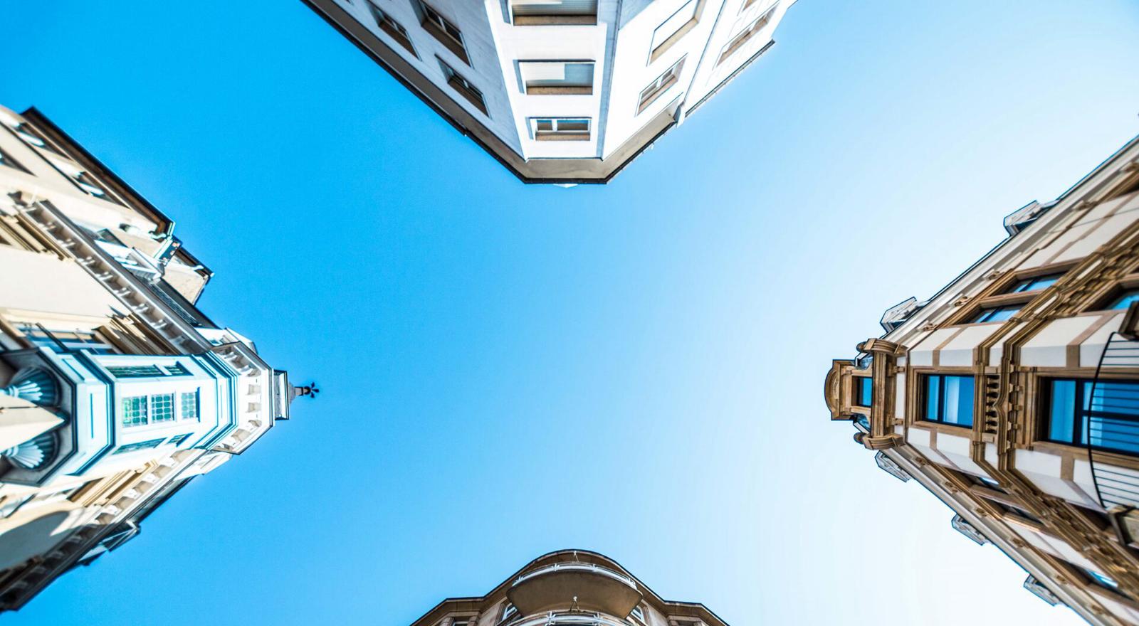 Large Web and Screen Worm's eye view of four building corners and a clear blue sky