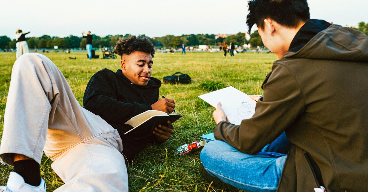 LinkedIn and Facebook Two teenagers sat on the grass drawing in a park