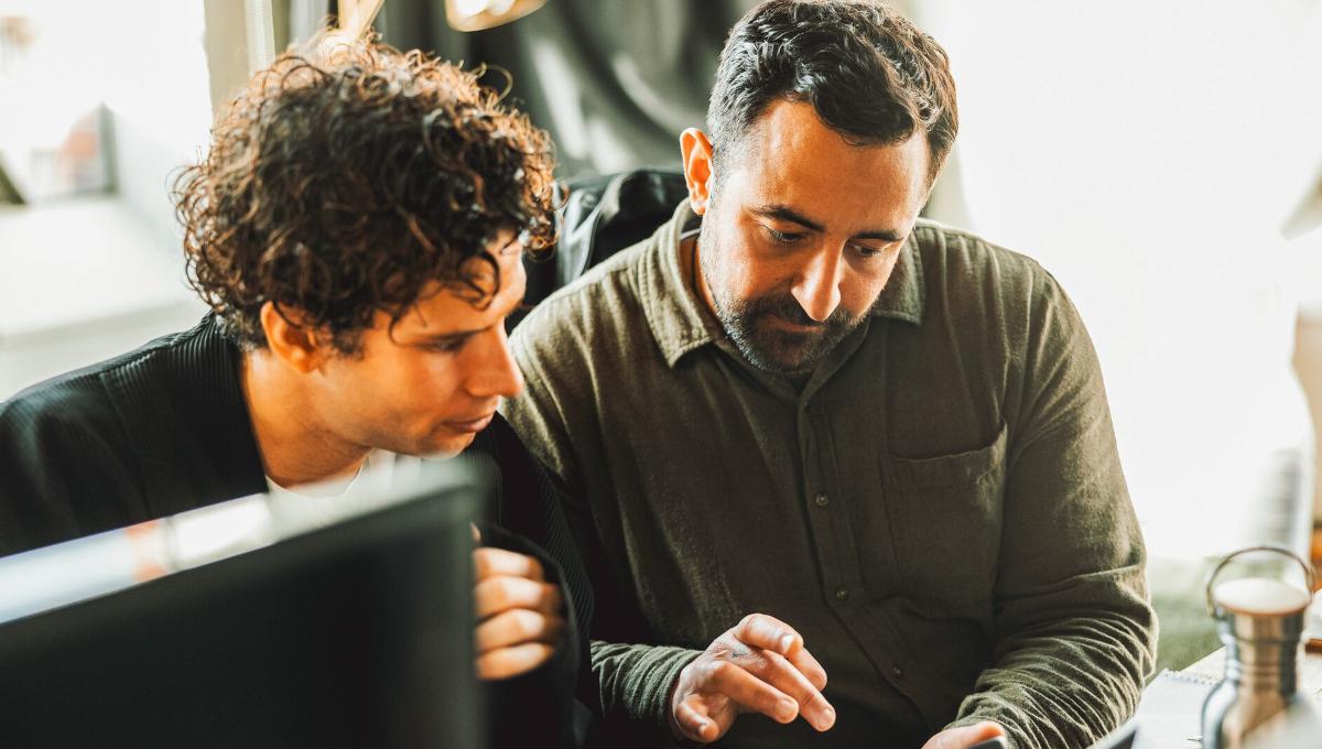 Two male colleagues look at phone