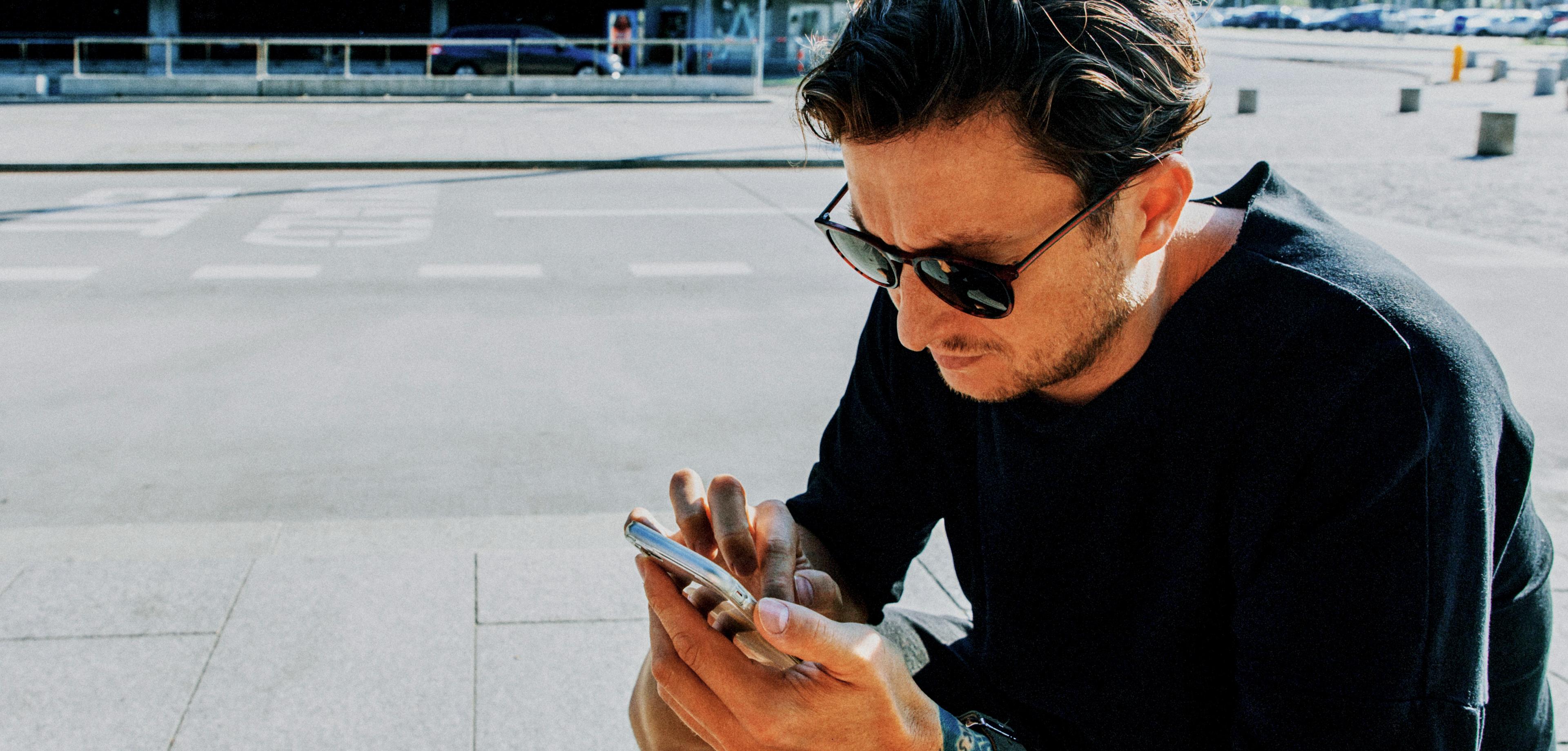 Young man using mobile phone while sitting large